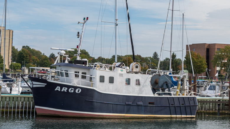 A large sailing vessel resting in the Dunkirk City Pier with a number of boats in the background.