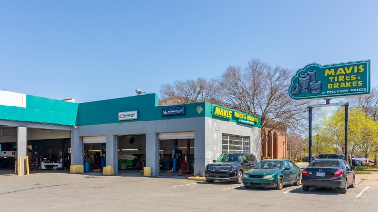 The exterior of a Mavis Tires and Brakes shop with cars parked outside of it.