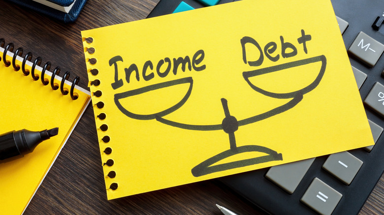 income and debt on scale drawn on post-it note