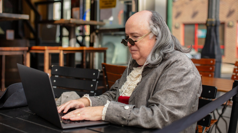 a Benjamin Franklin impersonation actor on a laptop