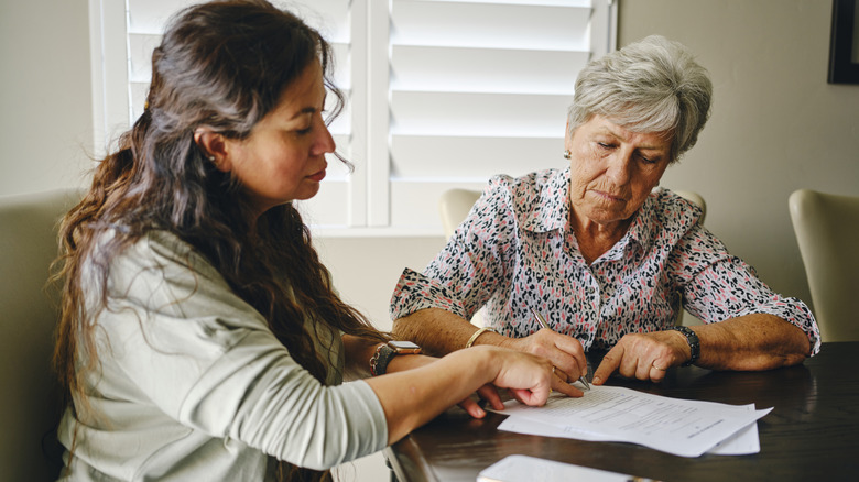 Older woman filling out documents with younger woman