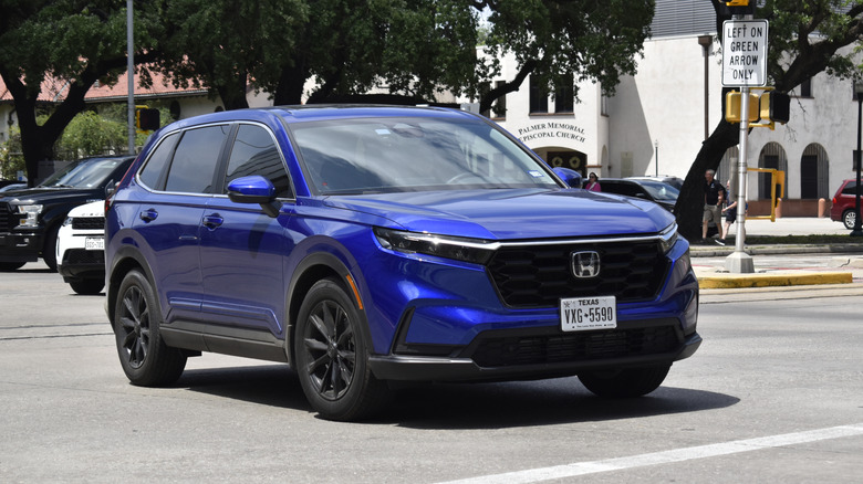 A blue Honda CR-V Hybrid luxury SUV driving on a city street.