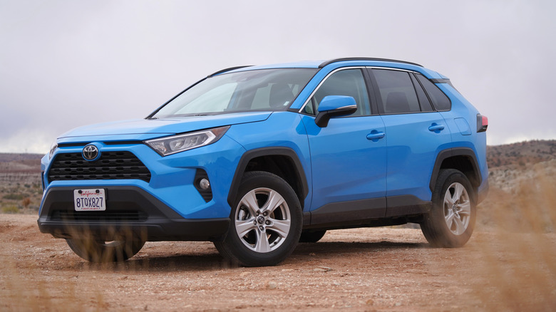 Blue Toyota RAV4 parked on a dirt road in the Utah wilderness with overcast sky.