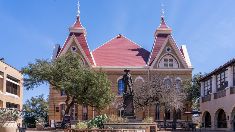 building with red roof and statue of cowboy