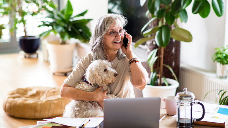 mature lady hugging dog with phone to her ear