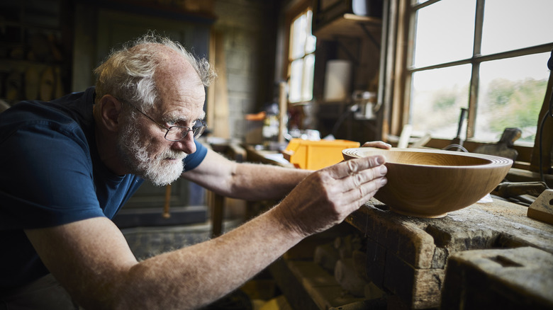 man with grey hair working on wooden bowl
