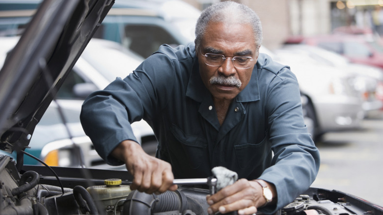 A mature mechanic working under the hood of a vehicle.