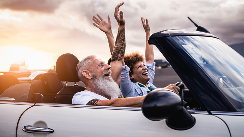 A mature couple enjoying a drive in a convertible car.