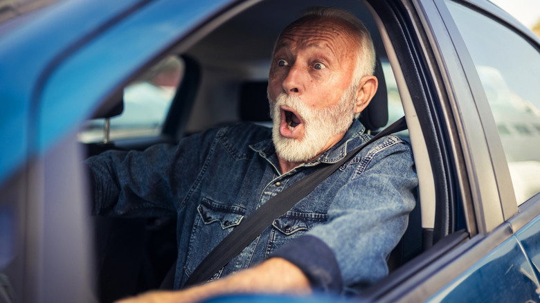 A frightened senior man screaming and braking just before an accident.