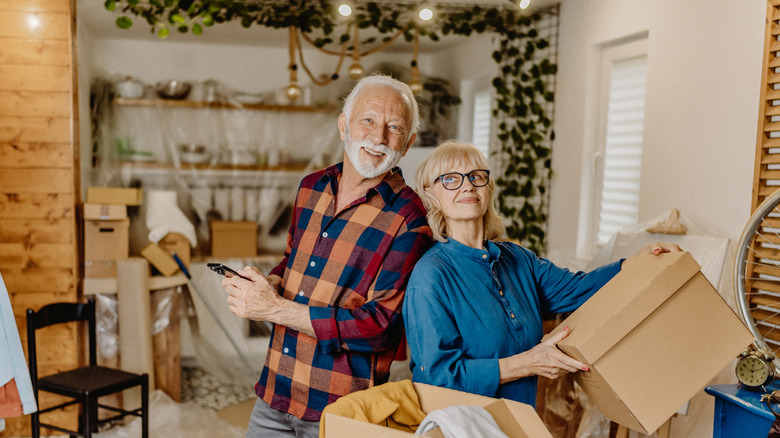 A senior couple moving in to a new home with moving boxes.