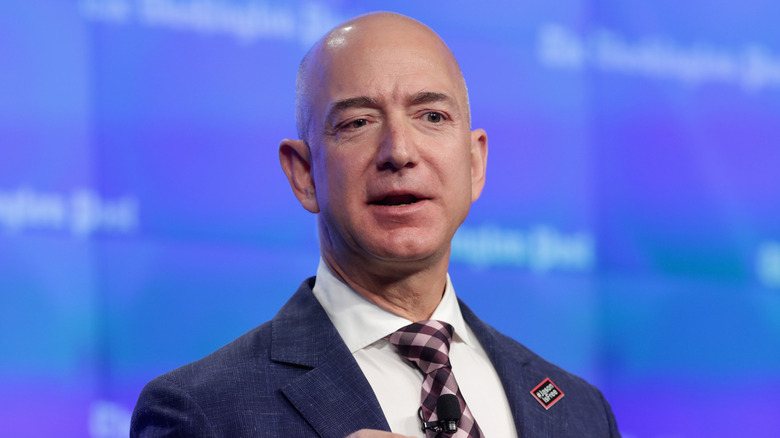 A closeup of Jeff Bezos giving a speech against a blue backdrop