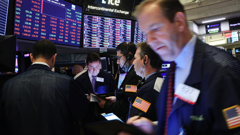 Traders on the floor of the stock exchange with screens behind them.