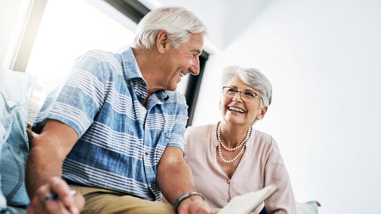an older couple laughs while handling paperwork