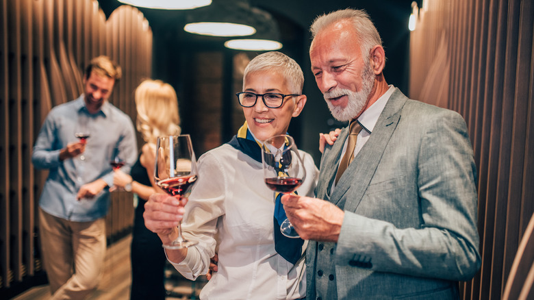 an older couple holding wine glasses at a winery
