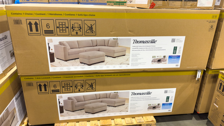 Beige Thomasville sofas packed up into cardboard boxes and stacked on a pallet on a Costco warehouse floor