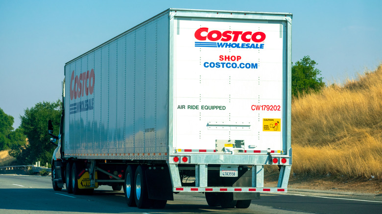 The back of a Costco delivery truck as it drives along a rural highway