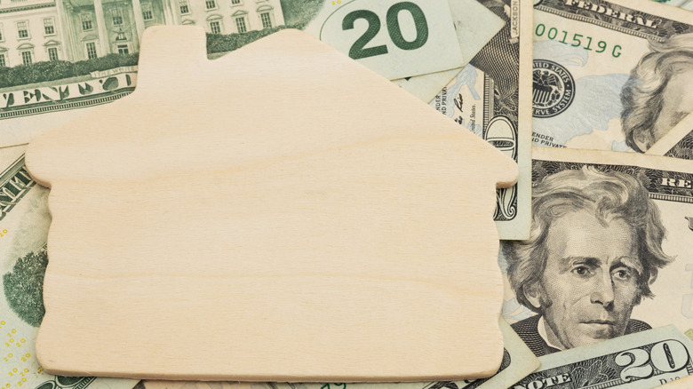 Blank house figure on top of multiple twenty dollar bills.