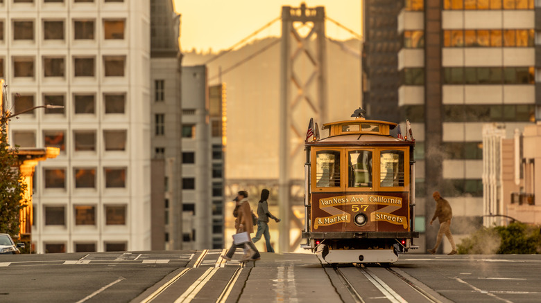 People crossing the street in San Francisco with a trolly.