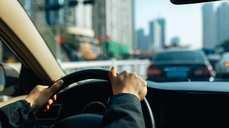 Close-up of hands on a steering wheel of a car.