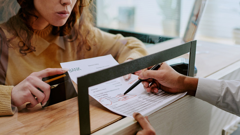 Woman filling out a bank form with a teller