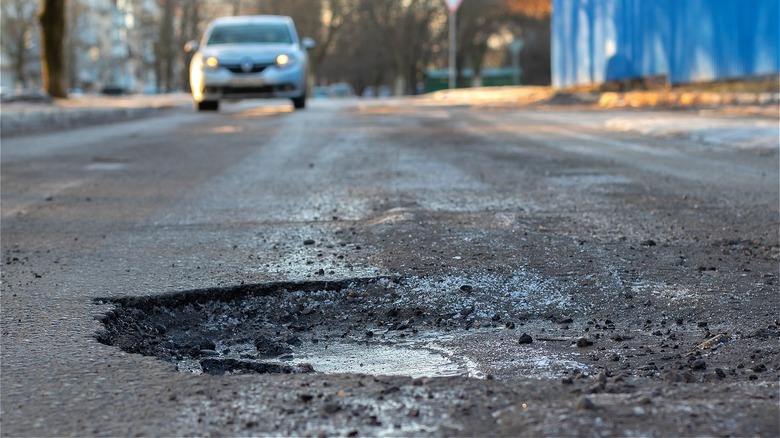 Car approaching road pothole