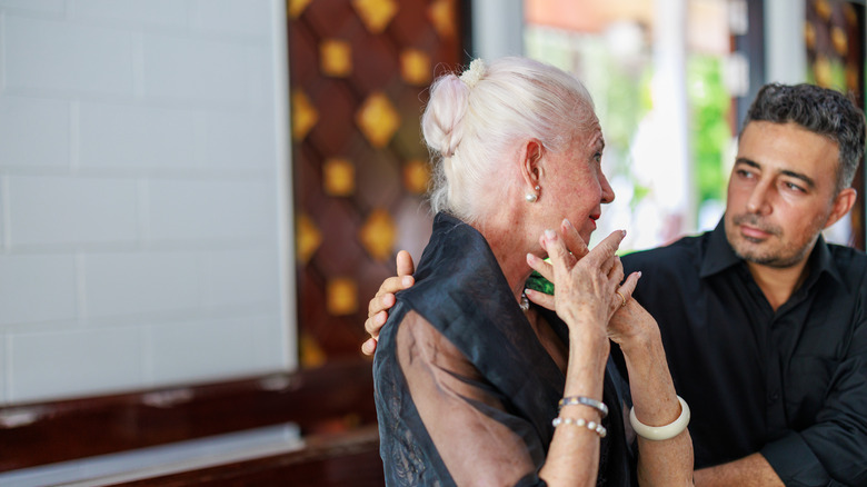 A senior woman and her son participate in a funeral ceremony at a Catholic Church