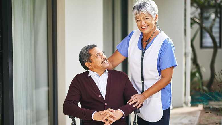 Senior, man and wheelchair at retirement home with nurse for medical, health and wellness care by caregiver