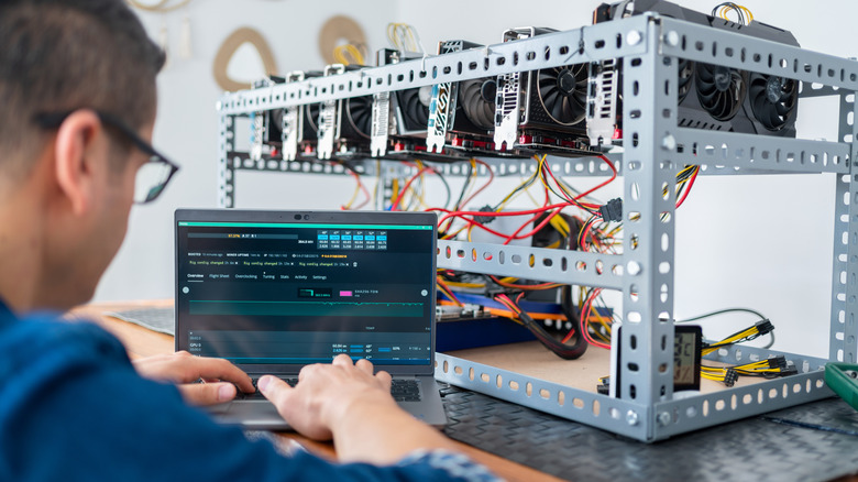 young man mines Bitcoin on a laptop from a home office