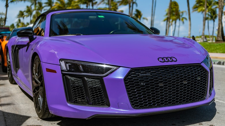 Purple Audi R8 supercar parked outdoors with palm trees in the background