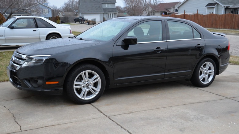 Black Ford Fusion sedan parked in a residential driveway on an overcast day