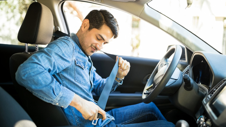 Young man fastening his seat belt.