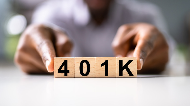 Person holding wooden blocks spelling out "401k"