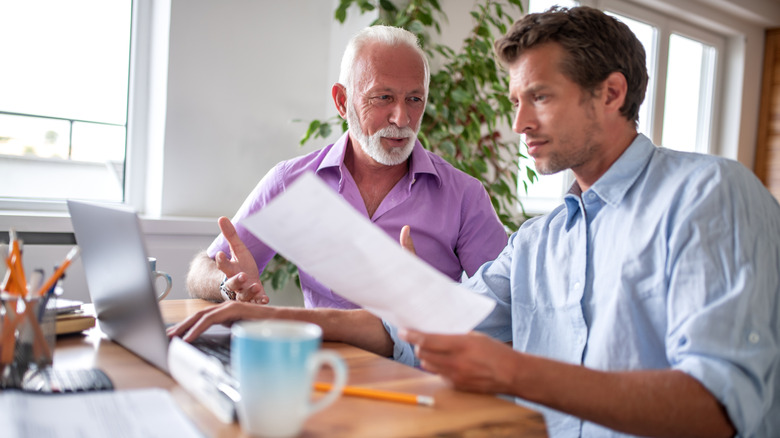 One older man and one younger man discussing work in office