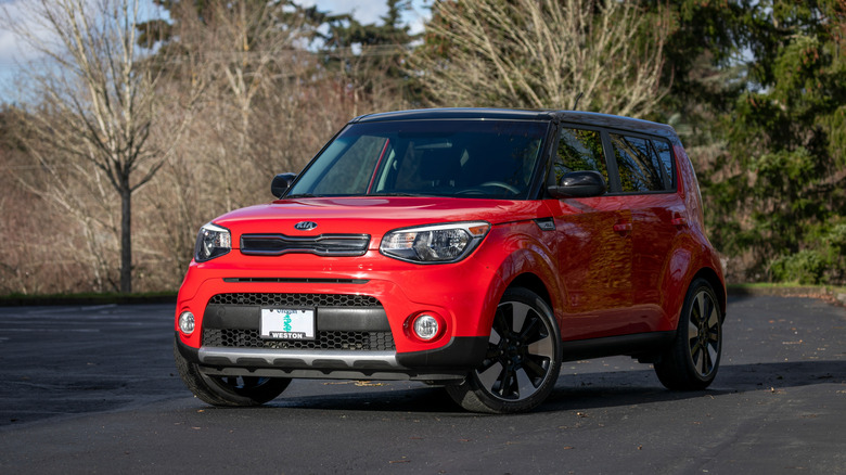 A red Kia Soul South Korean hatchback car parked outdoors in daylight.
