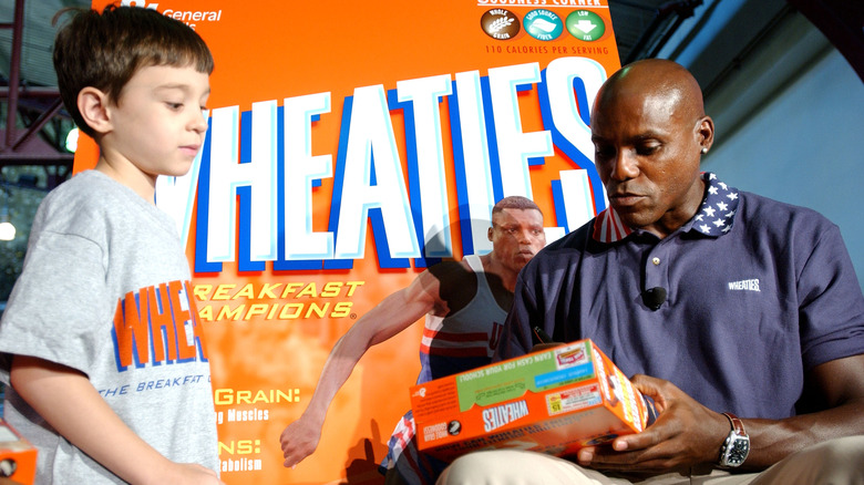 Athlete Carl Lewis signs a Wheaties cereal box