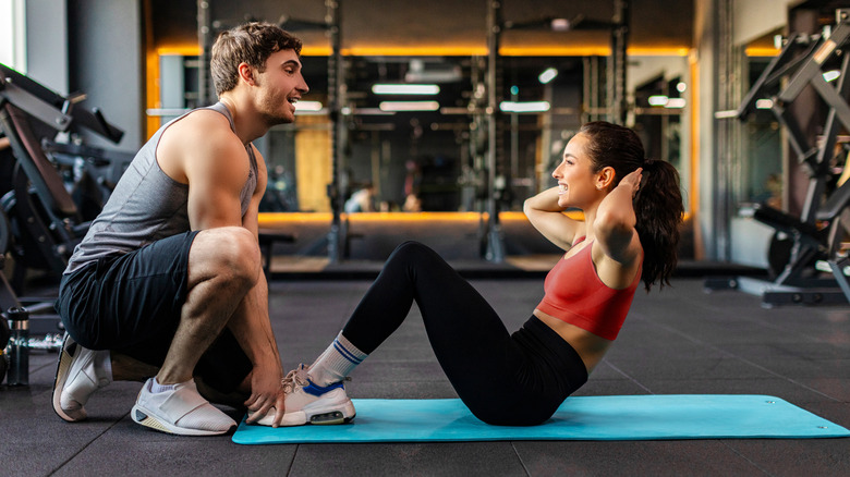 Women doing situps with help of trainer.