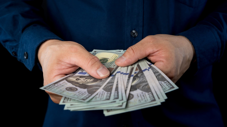 Person holding multiple hundred dollar bills.
