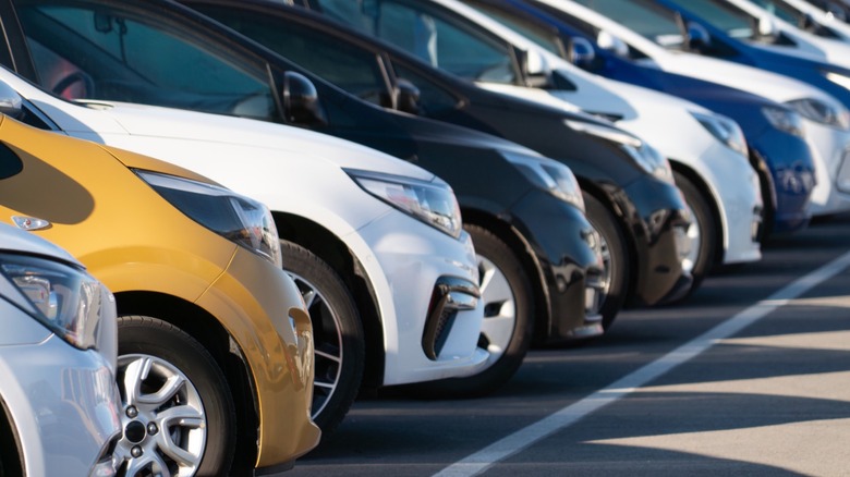 Different types of cars lined up for sale in a row on a used car lot.