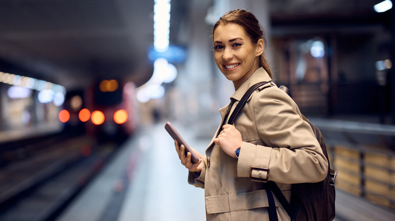 A young woman smiling as she waits for a subway train