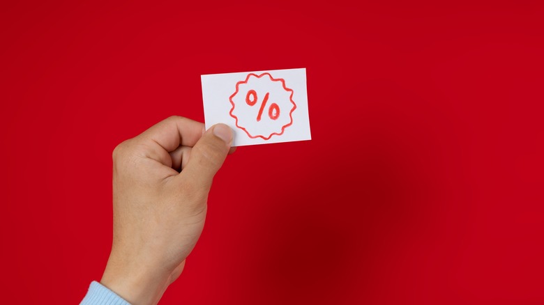 Male hand holding a discount card with a percentage sign on it
