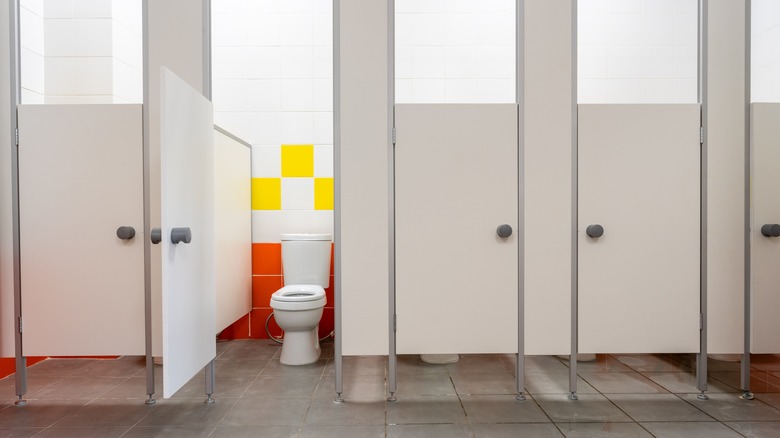 Clean public restroom with stalls and one stall door open