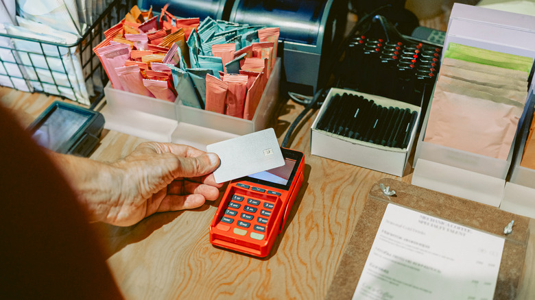 Man waving a credit card near a credit card reader
