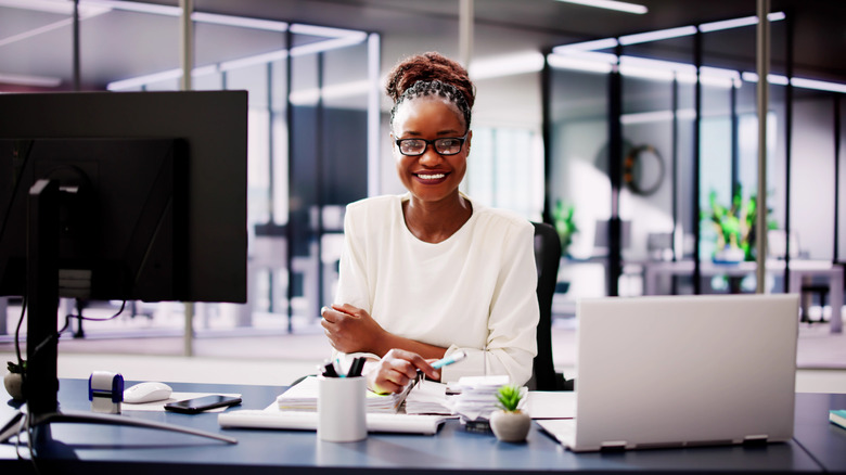 A smiling woman sitting behind a desk in a bright office