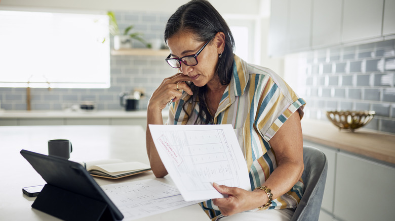 A perplexed woman looking at documents in her home.