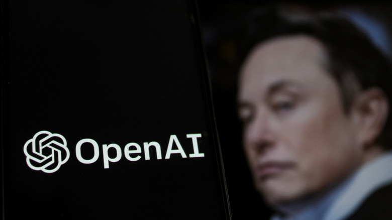 Open AI logo is seen displayed on a smartphone screen with Elon Musk Account photo profile in the background