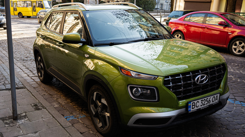 A green Hyundai Venue car parked on an urban street with city life in Lviv, Ukraine.