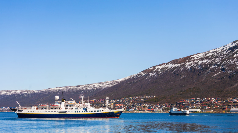 A small cruise ship in the ocean close to land.