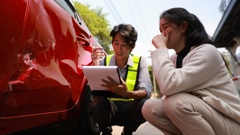 Woman and an insurance adjuster looking at car damage