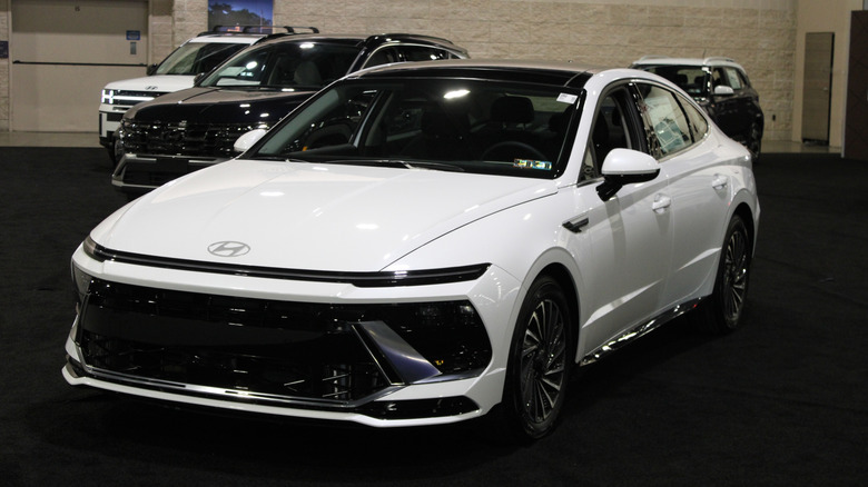 A white 2026 Hyundai Sonata Hybrid on display at an autoshow.