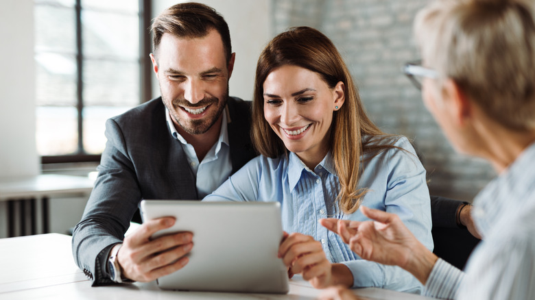 A happy couple looking at a tablet with their new auto insurance policy.